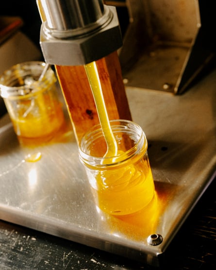 A machine fills jars with golden honey