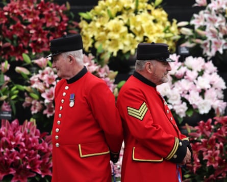 Chelsea pensioners wearing military dress standing in front of flower arrangements at the flower show