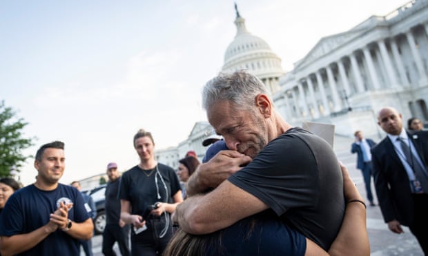 Jon Stewart hugs Rosie Torres, the wife of veteran Le Roy Torres, who suffers from illnesses related to exposure to burn pits in Iraq, in Washington DC on 2 August. 