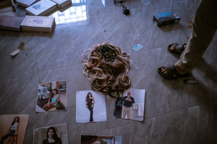 A blond wig and photos of young Asian women lie on the floor with books and other objects scattered around
