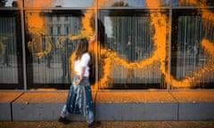 Young woman smearing orange paint on building
