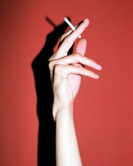 Closeup of forearm and hand of someone holding a cigarette