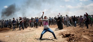 A Palestinian demonstrator in Abu Safia throws a stone towards Israeli positions