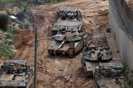 Four tanks sit on a muddy dirt road.