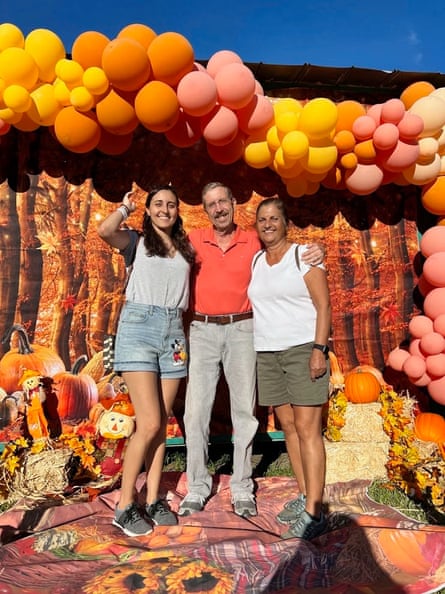 Family in front of arch of yellow, orange, and pink balloons.