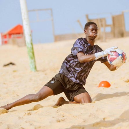 A man catches a football on a beach