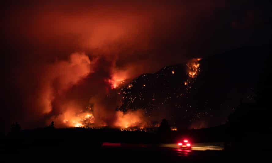 A motorist travels on the Trans-Canada Highway as a wildfire burns on the side of a mountain in Lytton, British Columbia, on Thursday.