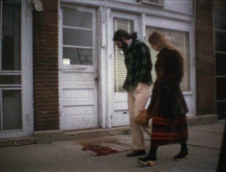 Two people walking slowly outside a building, in front of white slatted doors.