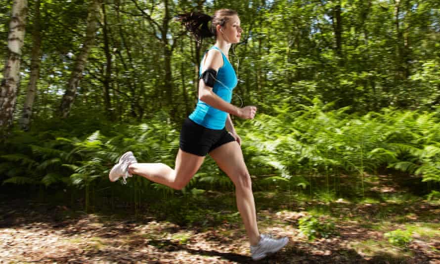 A woman running with a phone in an armband and earphones.
