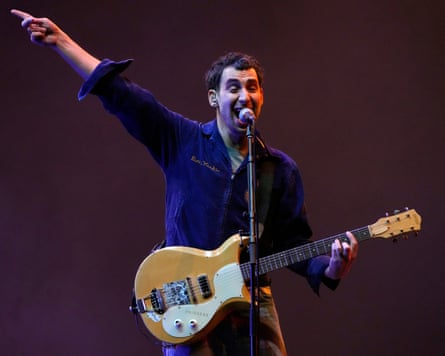 Jack Antonoff sings passionately into a microphone during a performance, arm raised in the air.