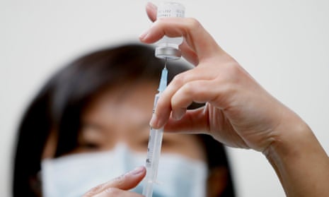 healthcare worker draws vaccine from vial