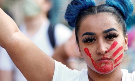 A woman with a red hand painted on her face, which calls attention to the high rates of Indigenous women who are murdered or missing.