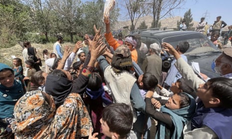 People reach for blankets being handed out in a Kabul park