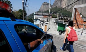 A woman walks past an armed police patrol in Rio de Janeiro’s Rochina favela community.