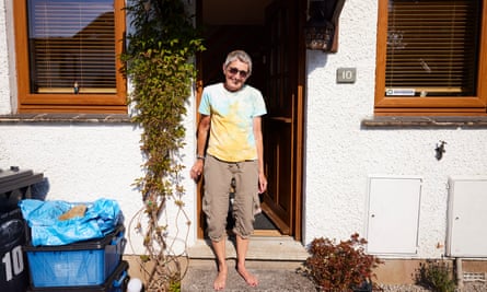 Woman stood outside whitewashed property with wooden windows and open door