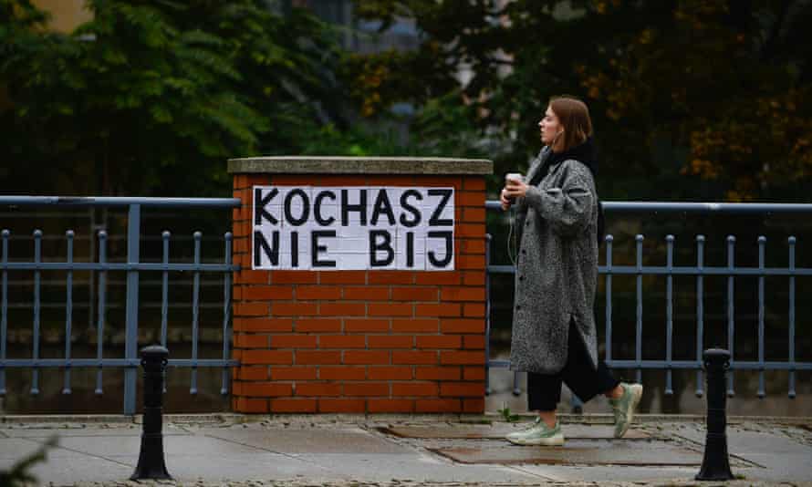 A woman in Wroclaw, Poland, walks by a poster inspired by Les Colleuses, that says: ‘You love, you don’t hit.’