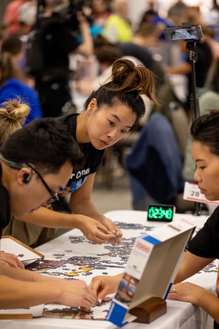 A team works on a puzzle, a clock on their table.