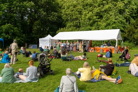 People sitting on grass by a marquee