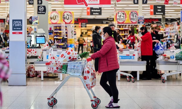 A shopper pushes a trolley outside a supermarket
