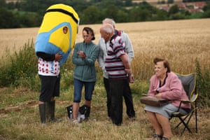 A spectator wearing a Minion costume watches on a mobile telephone as he waits along the roadside of the race route during the 2nd stage