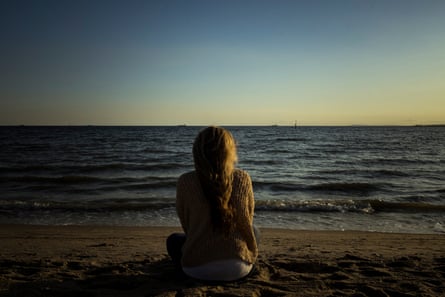 Woman sitting on beach facing sea