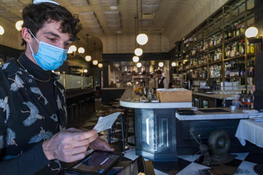 Joey Tyler, a restaurant host, verifies a patron's vaccination card at the Petit Trois in Los Angeles.