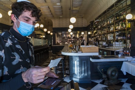 Joey Tyler, a restaurant host, verifies a patron’s vaccination card at Petit Trois in Los Angeles.