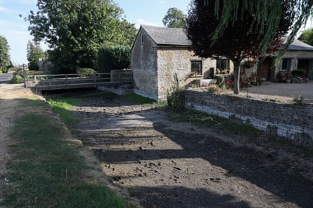 Dried-up mud on the riverbed of the Thames in a village with historic stone buildings and walls.