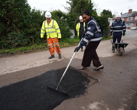 Badenoch filling a pothole as people in hi-vis watch on
