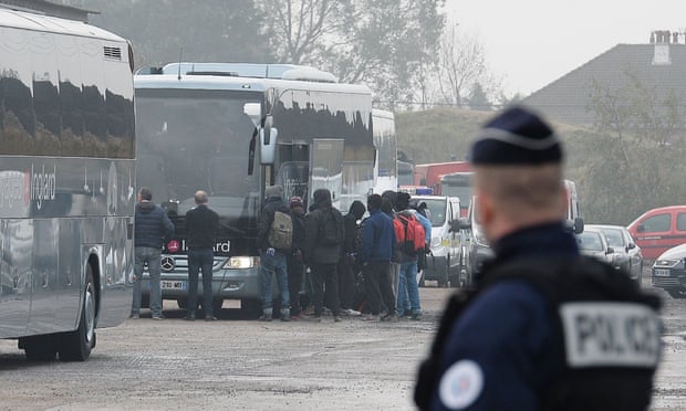 Migrants board buses after registering at a processing centre near Calais