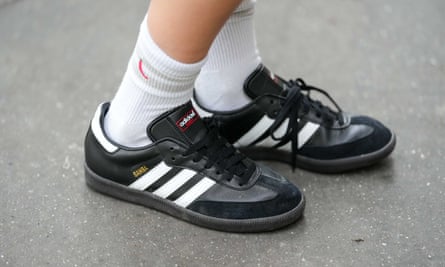 A person wearing black Adidas Sambas with white socks