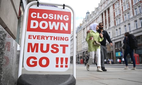 Shoppers pass a sign advertising a sale in London.