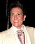 She wears a white suit and pink cravat