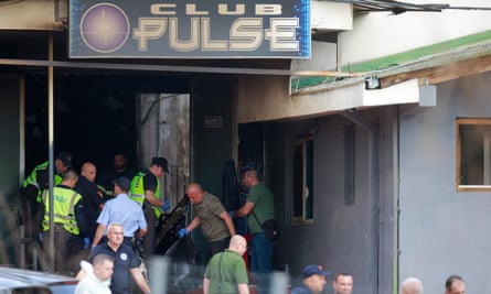 Police officers and others remove plastic bags from Club Pulse