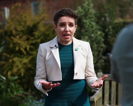 Carla Denyer gesturing in green dress and cream jacket