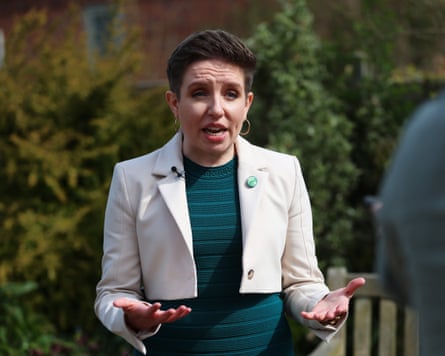 Carla Denyer gesturing in green dress and cream jacket