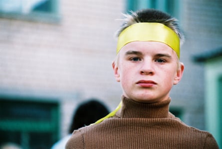 A boy with a yellow ribbon tied around his head stares at the camera.