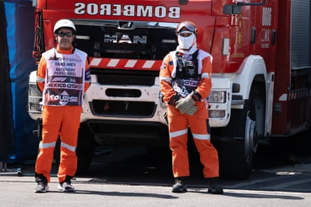 Two firefighters in fire retardant overalls stand in front of their fire truck in the pit lane at the Mexico Grand Prix.