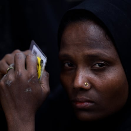 A Rohingya woman holds her identity and work cards