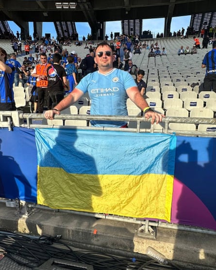 Yaakov Kris, fan de Manchester City, posant avec le drapeau ukrainien au stade de football.