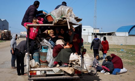 People sitting on a truck loaded with belongings