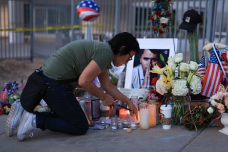 A woman lights one of the many candles in front of a portrait of Charlie Kirk on the sidewalk