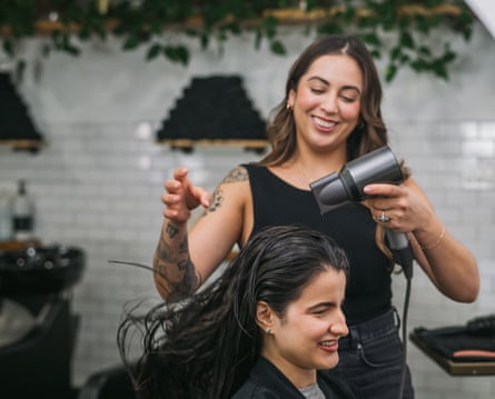Female stylist blow-drying a woman’s hair in a salon
