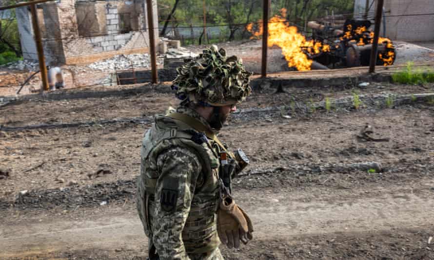 A Ukrainian soldier walks past a burning natural gas terminal on the northern outskirts of Kharkiv.