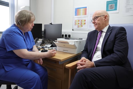 Ο John Swinney μιλάει σε έναν επαγγελματία υγείας σε μια κλινική.