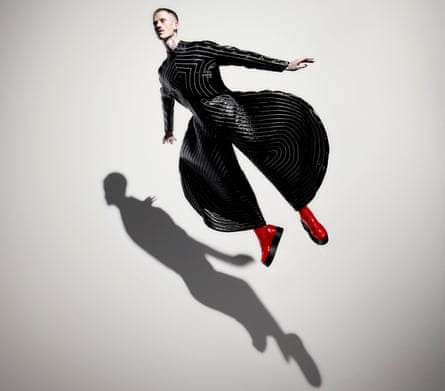 A dancer in a striped black coat and red boots leaps in a David Bowie tribute performance