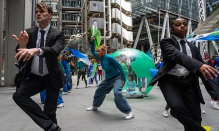 Dancers circle a young girl in an inflatable Earth to protest against climate change outside a City of London building