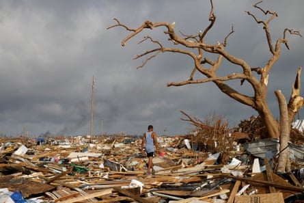 man walks among debris and a dead tree