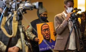 A man holds a portrait of George Floyd during a press conference on the third day of jury selection at the trial of former Minneapolis police officer Derek Chauvin on Wednesday.