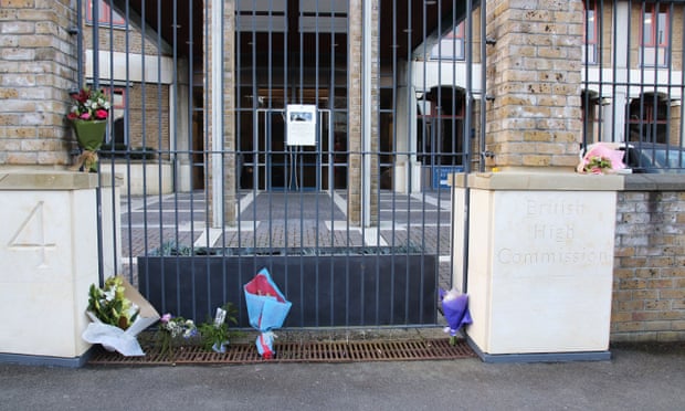 Six bunches of flowers resting against a gate
